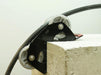 A 90 degree cable guide roller with a robust metal frame and heavy-duty aluminium rollers designed to pull cables gently around corners. Example photo showing roller attached to the corner of a concrete block.
