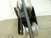 A 90 degree cable guide roller with a robust metal frame and heavy-duty aluminium rollers designed to pull cables gently around corners. Example photo showing roller attached to the corner of a concrete block.